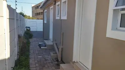 a small alley way with a building and a wall at The Brookston Garden Cottage in Cape Town