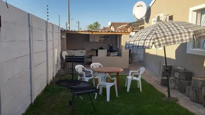 a patio with a table and chairs and an umbrella at The Brookston Garden Cottage in Cape Town