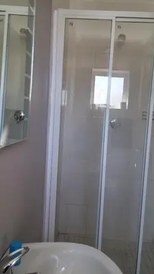 a bathroom with a shower and a white sink at The Brookston Garden Cottage in Cape Town