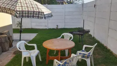 a table and chairs and an umbrella in a yard at The Brookston Garden Cottage in Cape Town