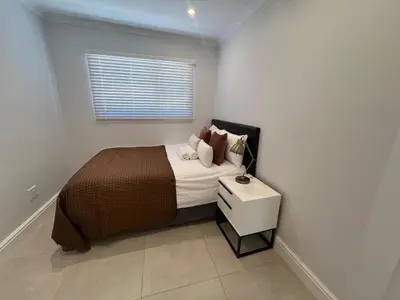 a bedroom with a bed with a nightstand and a window at 4 sleeper Lamsyh Apartment in Cape Town