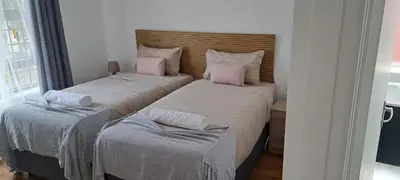 two beds in a small room with pink pillows at MBCholidayhouse in Cape Town