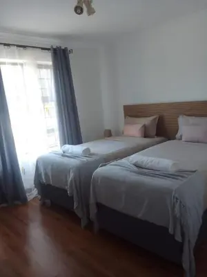 two beds in a bedroom with a window at MBCholidayhouse in Cape Town
