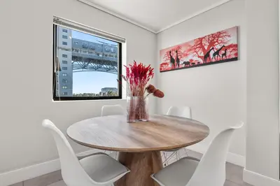 a dining room with a wooden table and white chairs at Waters Edge Luxury Apartment Century City in Cape Town