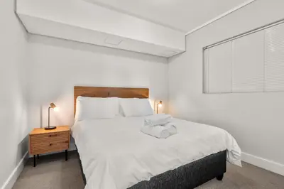 a white bedroom with a large bed and a window at Waters Edge Luxury Apartment Century City in Cape Town