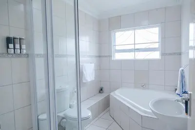 a white bathroom with a toilet and a sink at Vredekloof Views in Cape Town
