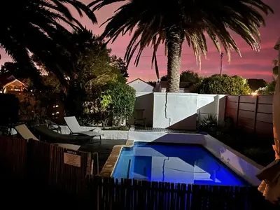 a swimming pool in front of a house with palm trees at 2stay Apartment Protea - Cape Town Bloubergstrand in Cape Town