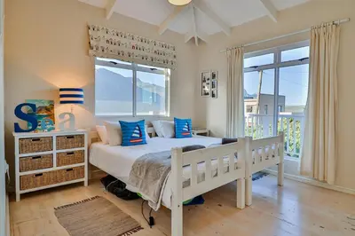 a bedroom with a white bed with blue pillows at Tides in Bettyʼs Bay