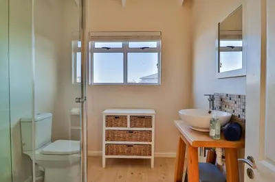 a bathroom with a sink and a toilet and a mirror at Tides in Bettyʼs Bay