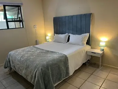 a bedroom with a large bed with a blue headboard at Cute Tranquil Pool Side Apartment in Cape Town