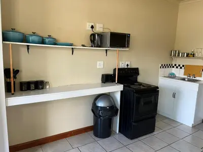a kitchen with a counter with a microwave and a stove at Cute Tranquil Pool Side Apartment in Cape Town