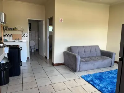a living room with a couch and a kitchen at Cute Tranquil Pool Side Apartment in Cape Town