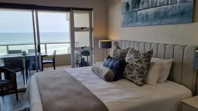 a bedroom with a bed with a view of the ocean at Beachfront Apartment with Amazing Views on Kite Surfing Beach in Cape Town