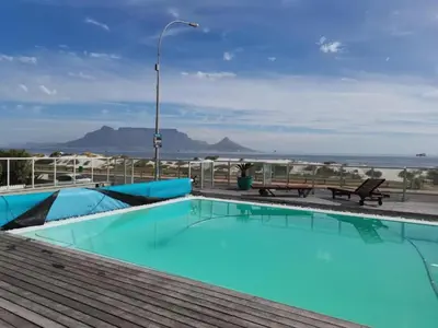 a swimming pool with a view of the beach at Beachfront Apartment with Amazing Views on Kite Surfing Beach in Cape Town