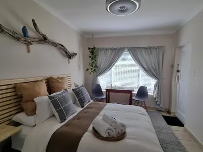 a bedroom with a large bed and a desk at Featherbed in Hermanus