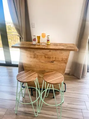 a wooden bar with two drinks and two stools at 155 Hangklip self catering in Pringle Bay