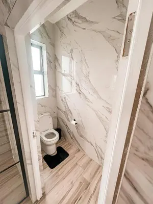 a bathroom with a toilet and a marble wall at 155 Hangklip self catering in Pringle Bay