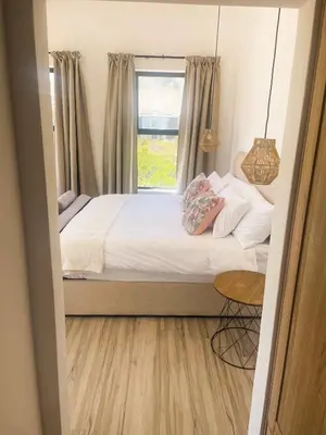 a bedroom with a bed with a window and a table at 155 Hangklip self catering in Pringle Bay