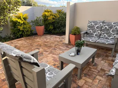 a patio with a couch and a table and chairs at Cozy Cottage in Cape Town