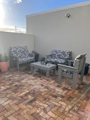 a patio with two benches and a table and chairs at Cozy Cottage in Cape Town