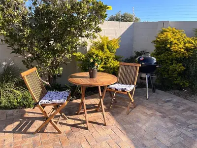 a wooden table and two chairs and a grill at Cozy Cottage in Cape Town