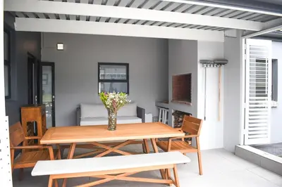 a table with a vase of flowers on a patio at MOS-Palmiet 72 in Kleinmond