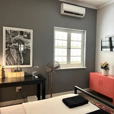 a bedroom with a bed and a desk and a fan at Spacious Stays Residence in Paarl