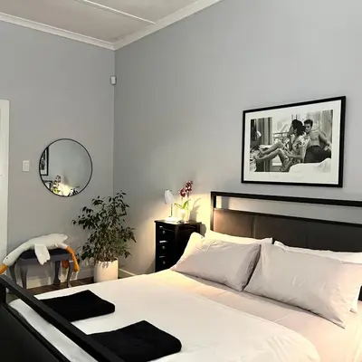 a bedroom with a white bed and a mirror at Spacious Stays Residence in Paarl