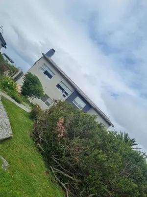 a house on a hill with bushes in front of it at OceansCrest Seaview Apartment in Bettyʼs Bay