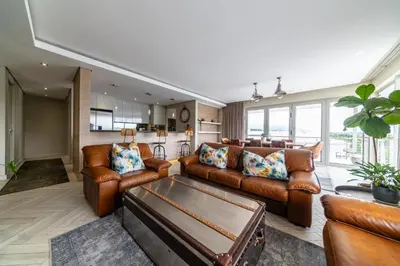 a living room with brown leather furniture and a kitchen at Apartment 206 Andringa Walk in Stellenbosch