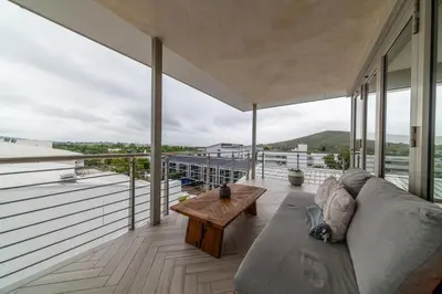 a living room with a couch and a table on a balcony at Apartment 206 Andringa Walk in Stellenbosch