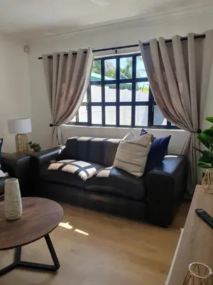 a living room with a black leather couch and window at Lynwood Place in Cape Town