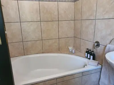 a bath tub in a bathroom next to a sink at Lynwood Place in Cape Town