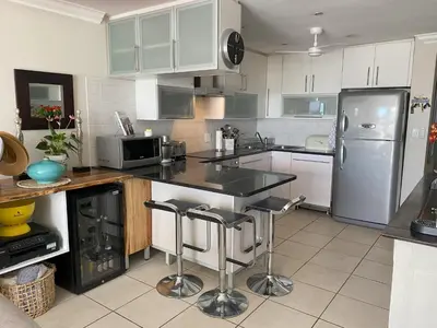 a kitchen with white cabinets and a stainless steel refrigerator at Bright apartment in Cape Town