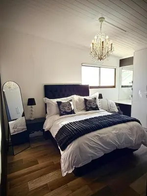 a bedroom with a large bed and a chandelier at Dior Maison de Reve- Private Penthouse in Stellenbosch