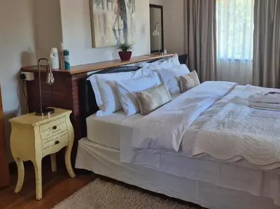 a bedroom with a large bed and a night stand at Afton Safari Lodge in Cape Town