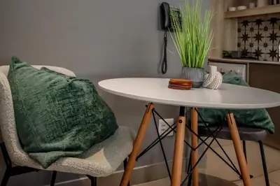 a white table and a chair with a green pillow at 18 on The Den Studio Apartment in Stellenbosch