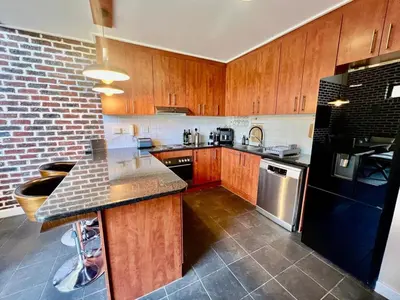 a kitchen with wooden cabinets and a black refrigerator at Enchanted View from Above in Stellenbosch