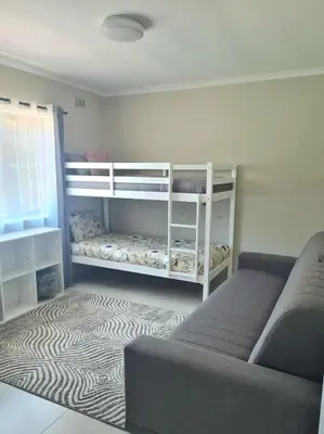 a bedroom with a bunk bed and a couch at Flamingle at Coot in Cape Town