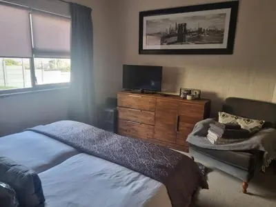 a bedroom with a bed and a tv and a chair at LaMer in Bettyʼs Bay