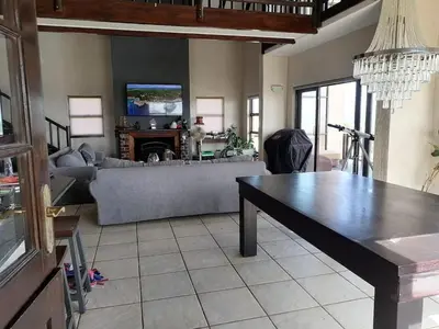 a living room with a couch and a table at La Mer in Bettyʼs Bay