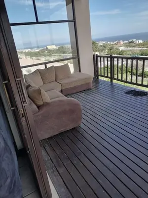 a couch sitting on the deck of a balcony at La Mer in Bettyʼs Bay