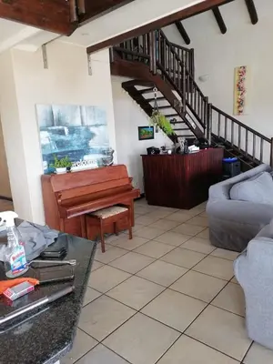 a living room with a piano and a couch at La Mer in Bettyʼs Bay