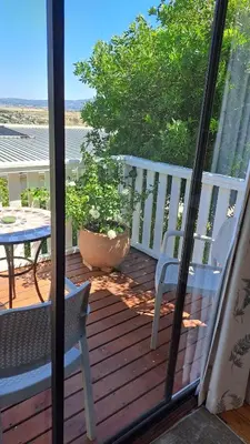 a balcony with a table and chairs on a deck at Martha's Place in Gordonʼs Bay