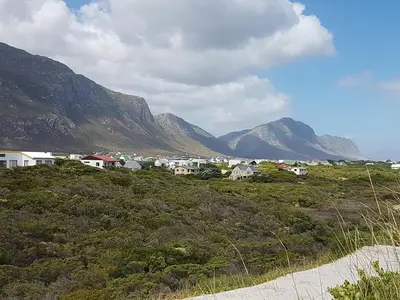 a group of houses on a hill with mountains in the background at Betty's Bay Quaint Cottage in Bettyʼs Bay