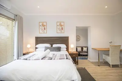 a bedroom with a large white bed and a desk at Lin's Snooze Inn in Strand