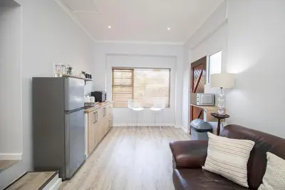 a living room with a couch and a kitchen at Lin's Snooze Inn in Strand