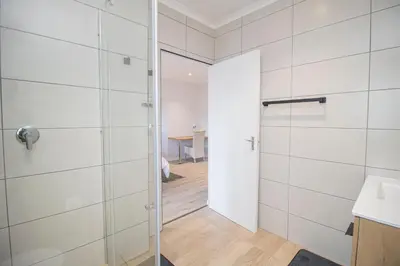 a bathroom with a shower and a glass door at Lin's Snooze Inn in Strand