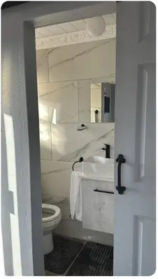 a white bathroom with a toilet and a sink at Malithabo in Khayelitsha