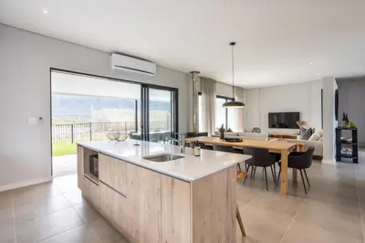 a kitchen and living room with a table and a dining room at Luxury Golf Villa 710, Pearl Valley Golf Estate in Simondium